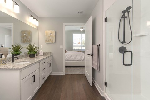 a bathroom with white cabinets and a shower and a bed